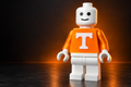 Tennessee-inspired Lego Man figure in an orange top with a white T, photographed against warm studio lighting
